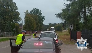 nieoznakowany radiowóz obok policjant, w tle policjant kontroluje pojazd