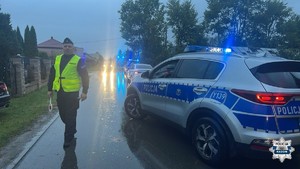 policjant i radiowóz w tle domy