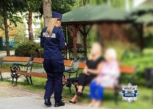 policjantka przekazuje ulotki kobietom siedzącym na ławce