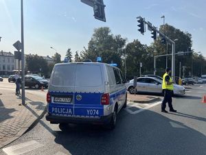 policjant i radiowóz na skrzyżowaniu blokuja wjazd