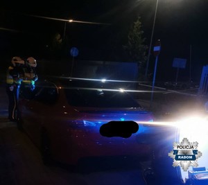 w nocy dwaj policjanci stoją przy aucie które kontroluja