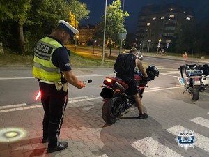 policjant stoi za motocyklem i sprawdza głośność