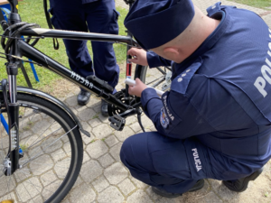 policjant tyłem kuca znakując czarny rower