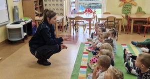 policjantka mówiąca do dzieci podczas spotkania w klasie przedszkolnej, dzieci siedzą i na dywanie i słuchają treści