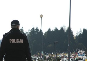 policjantka jest tyłem w tle nagrobki na cmentarzu