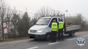 policjant i funkcjonariuszka strazy ochrony kolei stoja przy kontrolowanym aucie , funkcjonariusze sa tyłem