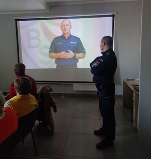 policjant prowadzący profilaktykę z seniorami w tle rzutnik