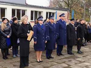 przed budynkiem szkoły stoi grupa osób , z przodu widac troje policjantów, przedstawiciela wojska i nauczycielkę w tle uczniowie