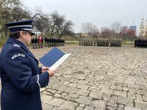 policjantka czyta list trzyma teczkę w tle grupa uczniów klas mundurowych