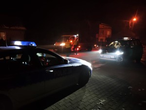 noc, radiowóz, w tle policjanci kontroluja pojazd