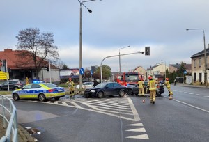 2 pojazdy uszkodzone po wypadku stoja na skrzyżowaniu, po lewej stronie widac radiowóz na miejscu pracuje kilku strażaków