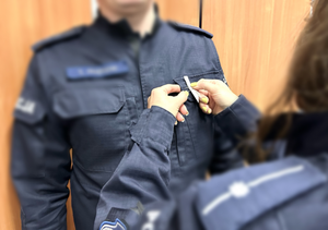 policjantka przypinająca policjantowi białą wstążkę do munduru