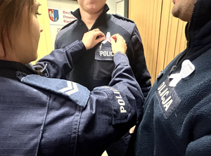 policjanci noszący symbol białej wstążki, policjantka przypina wstążke koledze