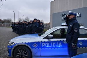 policjant przy radiowozie w tle grupa policjantów