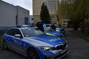 radiowozy a obok trzech policjantów