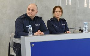 dwoje policjantów siedzi przy stole, po prawej policjantka, przed nia mikrofon