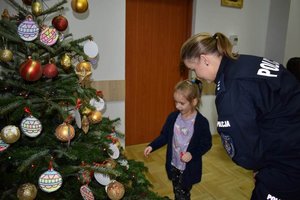 przy choince stoi policjantka i dziewczynka