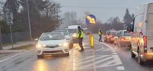 dwaj policjanci stoja na środku drogi kontroluja po dwóch stronach kierowców