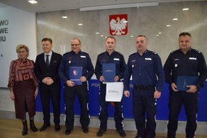 zdjęcie grupowe 4 policjantów, męzczyzna i kobieta po lewej stronie