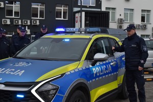 policjant przy radiowozie oznakowanym