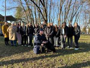 zdjęcie grupowe uczniowie opiekunowie ich a przed nimi policjant i pies słuzbowy