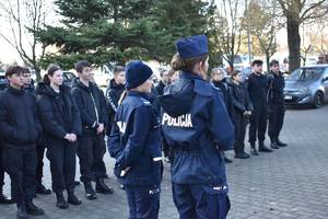 dwie policjantki a w tle uczniowie klasy mundurowej przed budynkiem komendy