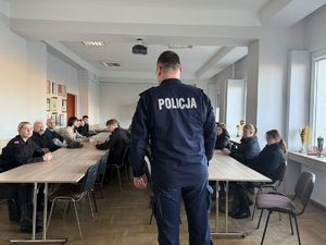 policjant w sali rozmawia z uczniami, widac go tyłem