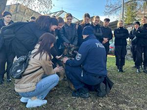 grupa uczniów podchodzi do przewodnika i jego psa słuzbowego