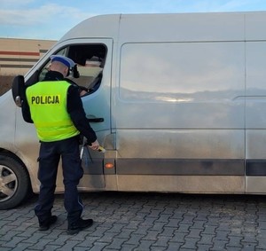 policjant stoi przy białym busie