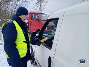 po lewej stronie policjant po prawej auto i kierowca którego kontroluje