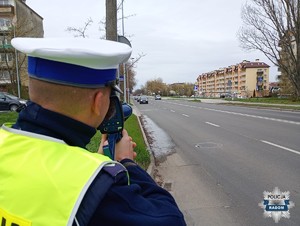 policjant tyłem do aparatu trzyma urządzenie do pomiaru prędkości