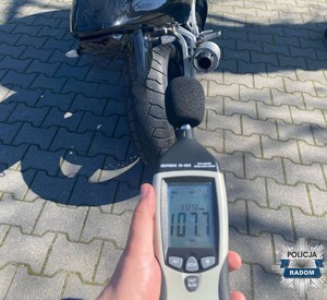 sonometr w dłoni mundurowego  w tle motocykl