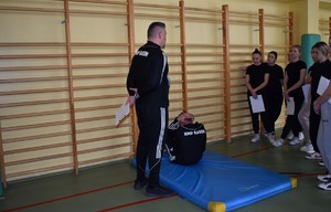 policjanci przy drabinkach na sali gimnastycznej pokazuja ćwiczenie obok obserwuja uczniowie