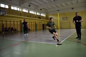 uczeń biegnacy na sali obok stoja policjanci