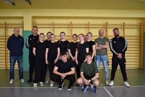 zdjęcie grupowe na sali, uczniowie dwaj opiekunowie i dwaj policjanci w strojach sportowych