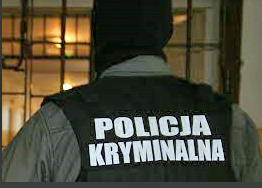 mężczyzna stojący tyłem w kominiarce w kamizelce z napisem policja kryminalna w tle kraty