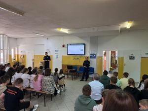 prelekcja dla uczniów w tle dwoje policjantów i ekran