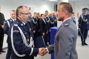 policjant stoi bokiem i odbiera wyróżnienie od Komendanta wojewódzkiego, widać uścisk dłoni
