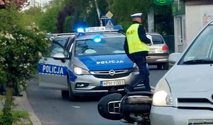 miejsce wypadku na ulicy lezy motocykl w tle widac policjanta i radiowóz
