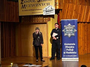 policjant i kobieta stoja na scenie podczas spotkania z młodzieżą