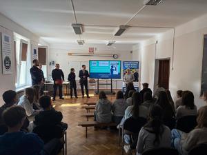 sala na której trwa spotkanie policjantów z uczniami, widac tyłem głowy uczniów w tle policjanci i kobieta