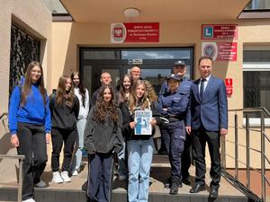na schodach przed budynkiem policjanci, grupa uczniów i przedstawiciel starostwa