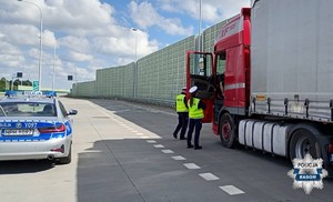 dwoje policjantów przy ciężarówce po lewej stronie zaparkowany radiowóz