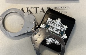 na teczce z aktami kajdanki i policyjna legitymacja