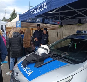 policjanci rozmawiaja z mlodzieżą obok radiowóz