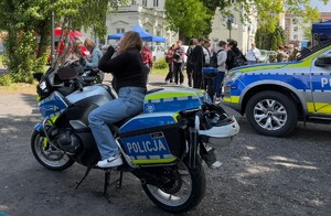 policyjny motocykl a na nim siedzi uczennica w tle grupa młodziezy i radiowóz