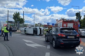 miejsce wypadku na rondzie jeden z pojazdów lezy na boku w tle policjanci