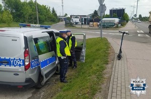 na pasie pieszo rowerowym hulajnoga elektryczna na poboczu radiowóz i dwaj policjanci