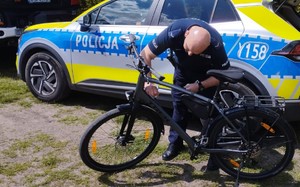 policjant znakuje rower za nim radiowóz