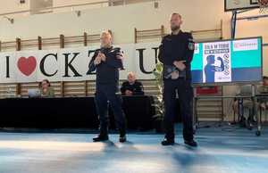 dwaj policjanci na sali podczas spotkania z uczniami